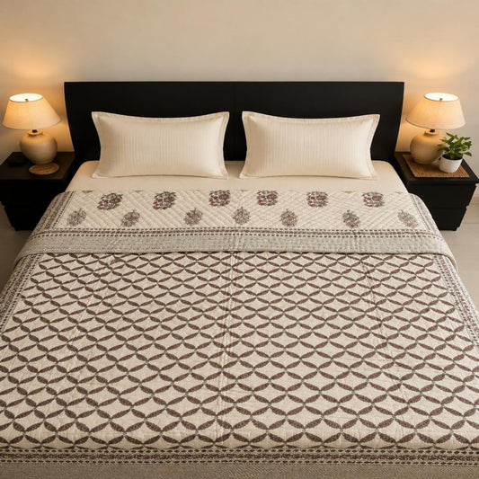 A neatly made bed in a bedroom setting, featuring a beautiful Jaipuri Razai/Comforter/Quilt with a burgundy geometric leaf pattern and a matching patterned runner, flanked by two cream pillows and black nightstands with lit lamps.