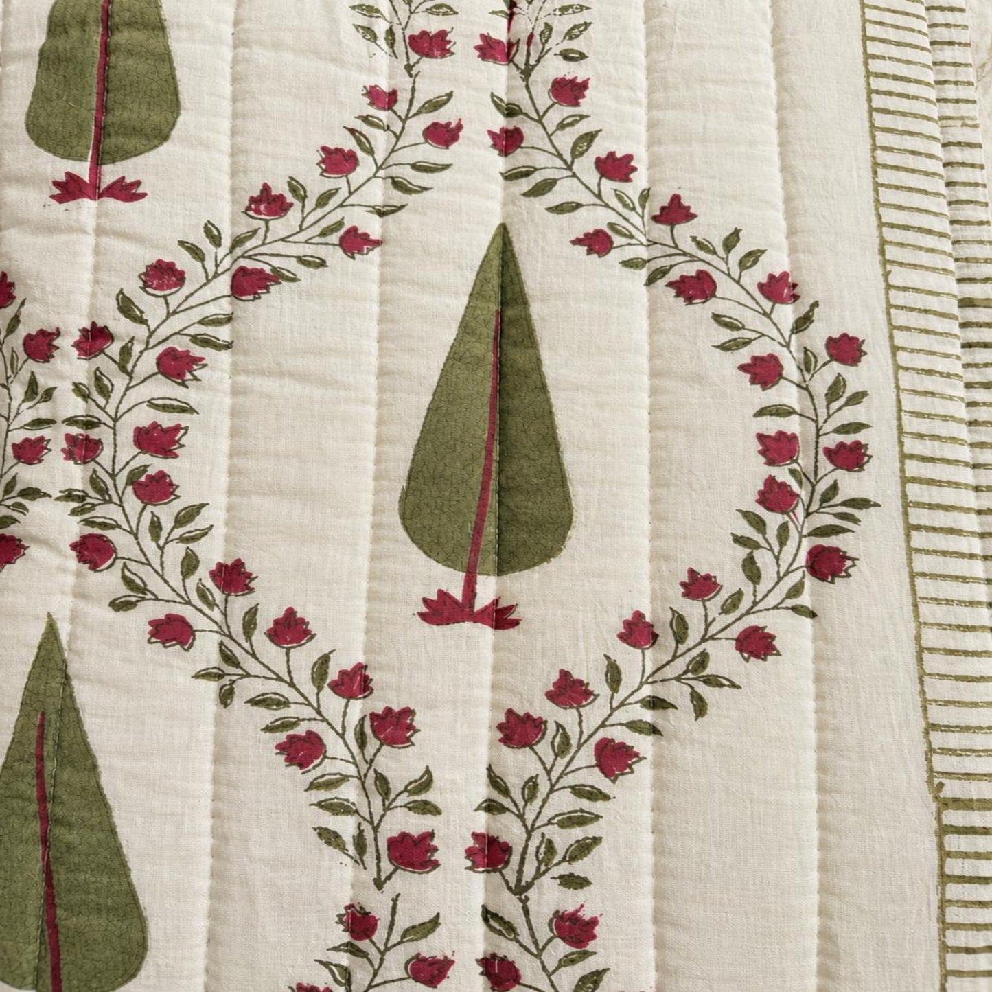 Close-up of a beautiful Jaipuri Block Print Razai with an off-white background, olive green teardrop motifs, and a border of small red flowers and green leaves.