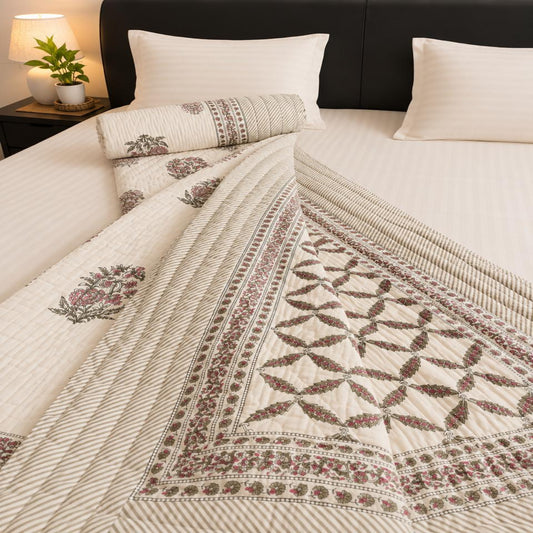 An off-white Jaipuri Razai with maroon geometric and floral patterns, styled on a bed with matching pillows and a dark brown headboard.