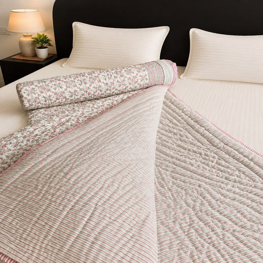 A cotton block print reversible comforter/Jaipuri razai, featuring a floral print on one side and stripes on the other.