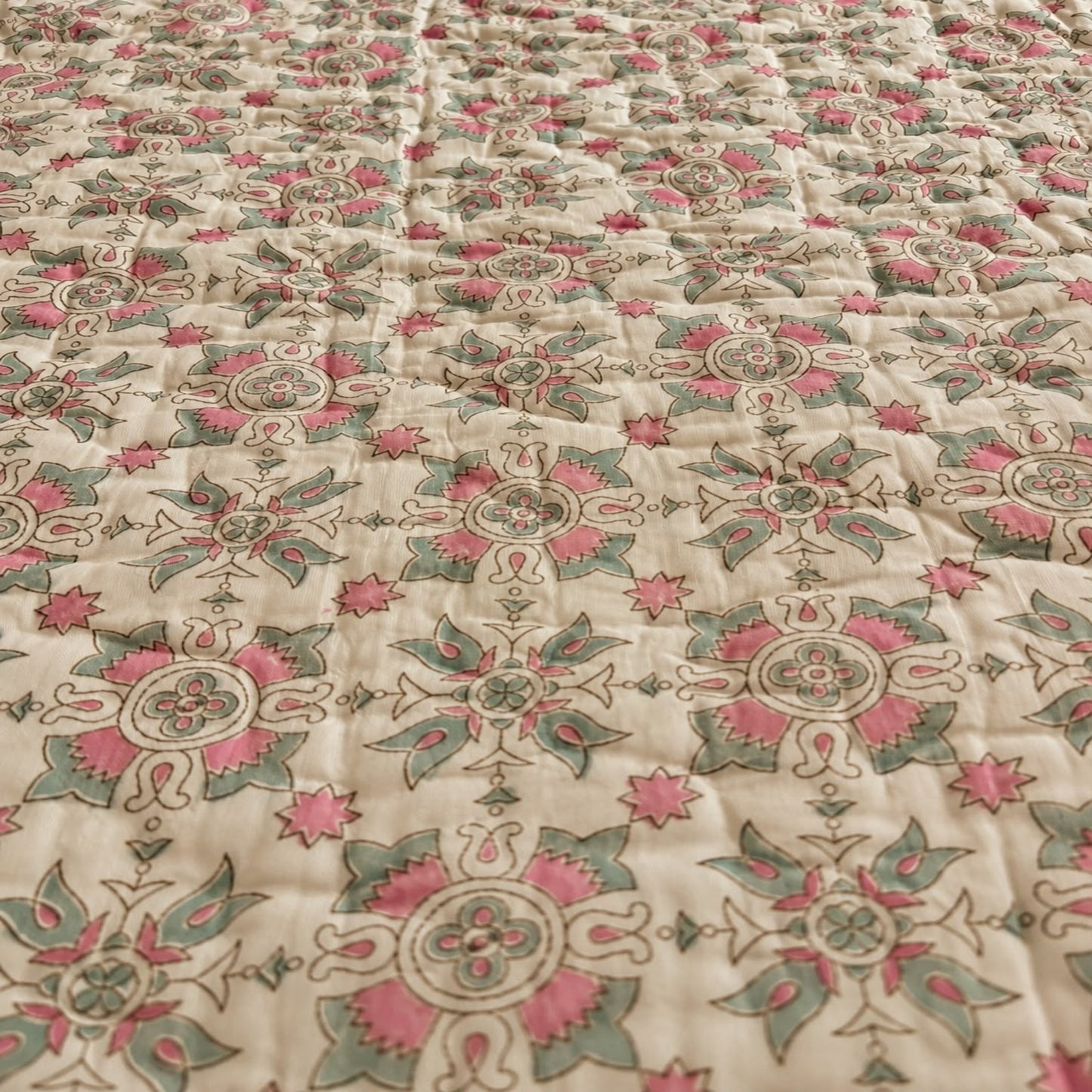 A close-up of the design featuring a traditional block-print floral pattern in pink, sage green and off-white.