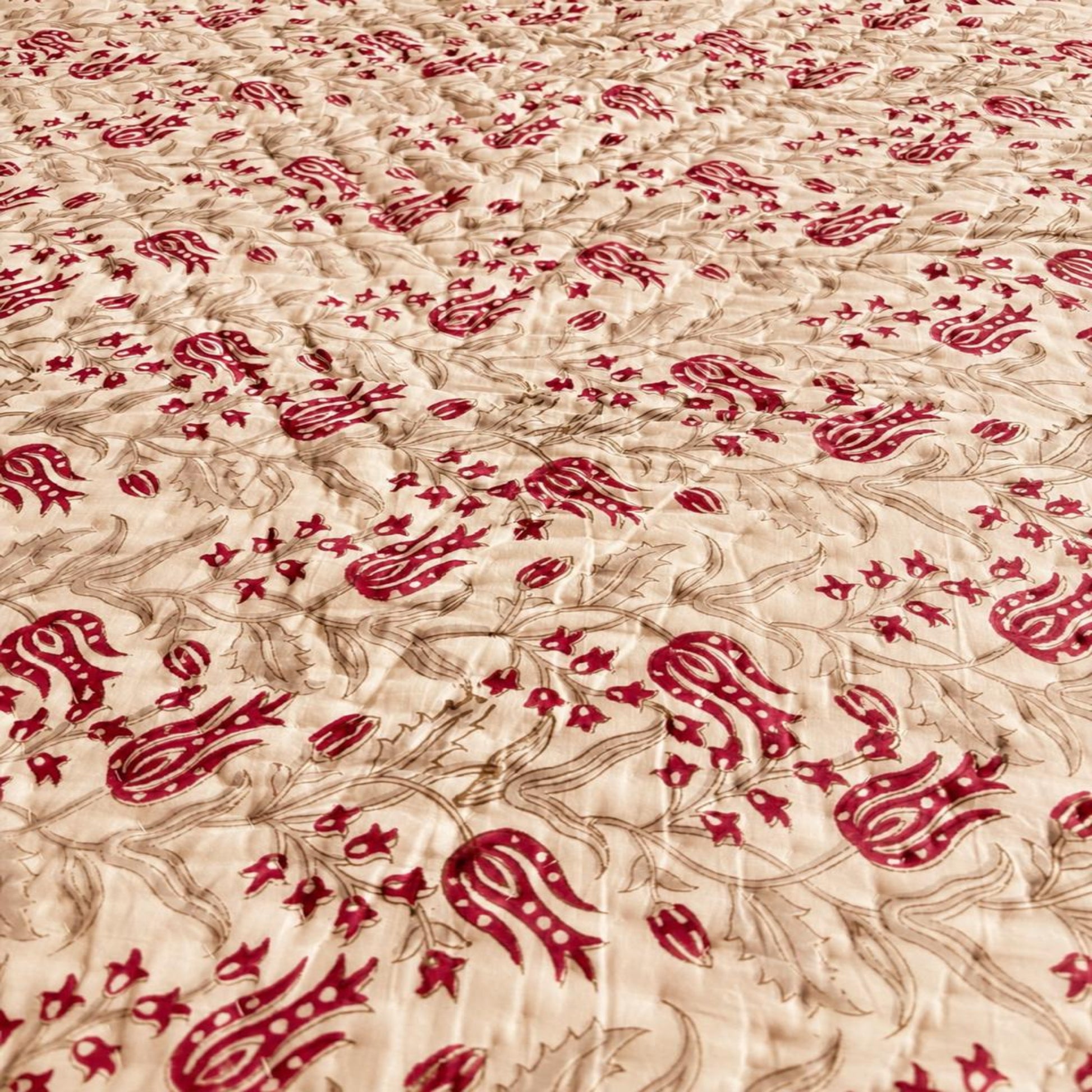 A close-up of the Razai featuring a repeating pattern of red stylized floral or calligraphic motifs 