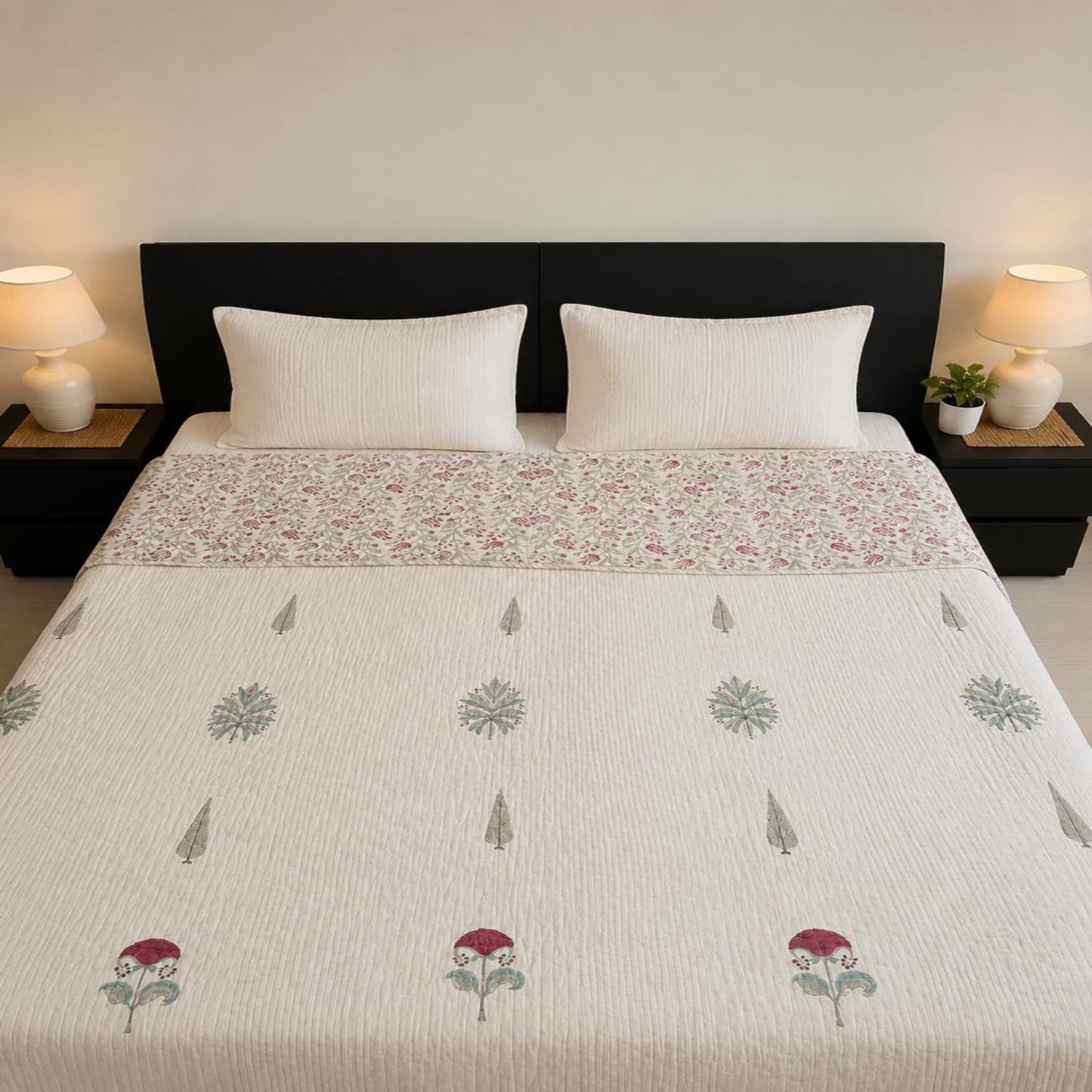 A neatly made bed in a bedroom setting, featuring a beautiful floral design Jaipuri Razai/quilt/comforter, accompanied by two white pillows and a dark headboard.
