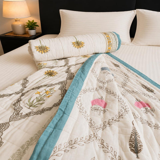 A Jaipuri Razai/Comforter with floral and geometric patterns, styled on a bed with matching white pillows and a rolled quilted pillow cover featuring beautiful print.